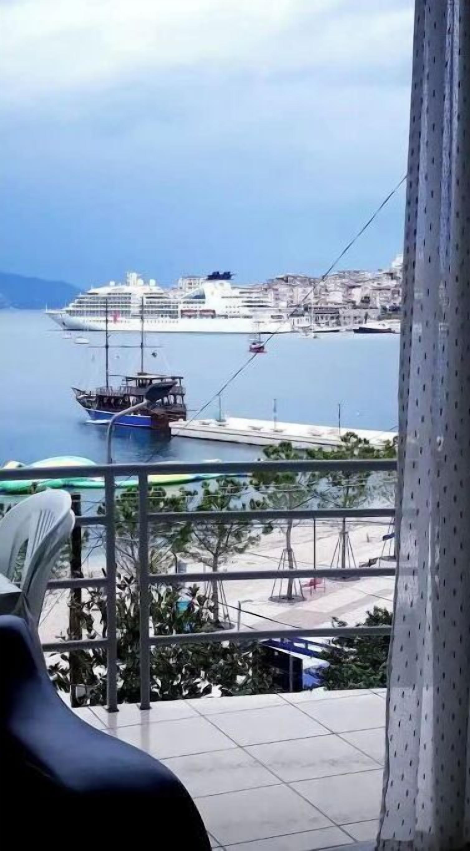 A balcony with a view of a cruise ship and a smaller boat in the water.