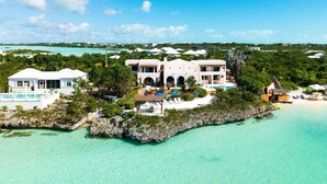 A coastal property with multiple buildings, a swimming pool, and a beach area.