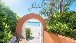 A pathway leading to a beach with a clear view of the sea and a few people in the distance.