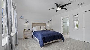 A bedroom with a bed, nightstands, a ceiling fan, and a window with curtains. - Ship To Shore-Close to Beach (North Palm Beach)