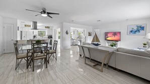 A spacious living area with a dining table, chairs, a sofa, and a TV. - Ship To Shore-Close to Beach (North Palm Beach)