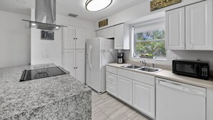 A modern kitchen with white cabinets, a built-in stove, a microwave, and a coffee maker. - Ship To Shore-Close to Beach (North Palm Beach)