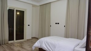 Quarto com cama, porta de correr de vidro e luminária no teto.