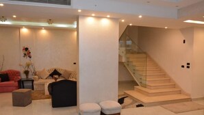 Uma sala de estar moderna com escada, sofá, pufes e um vaso decorativo.
