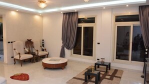 Uma sala de estar moderna com uma mesa de centro redonda, duas poltronas, um sofá e um lustre.