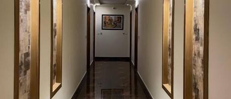 A corridor with mirrored walls, a ceiling light, and a framed picture on the wall.