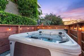 Ein Whirlpool in einer Außenanlage mit Holzterrasse und Lichterkette.