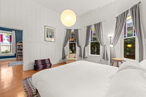 Ein Schlafzimmer mit einem großen Bett, einem Sessel, einem kleinen Tisch und einem Bücherregal.