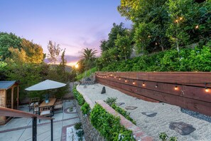Eine Terrasse mit Holzdeck, Gartenmöbeln und einer Gartenmauer mit Lichterketten.