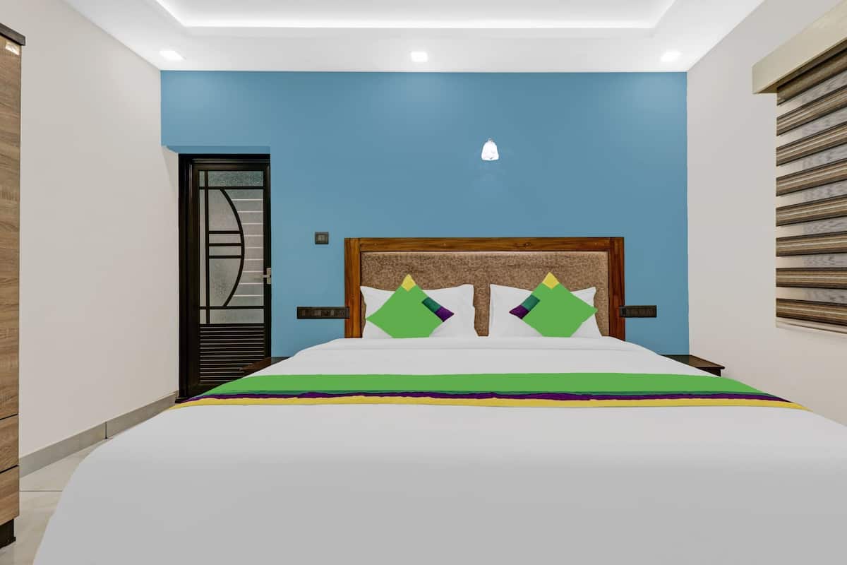 Un dormitorio con una cama, cabecera de madera, pared azul y ventana con persianas.