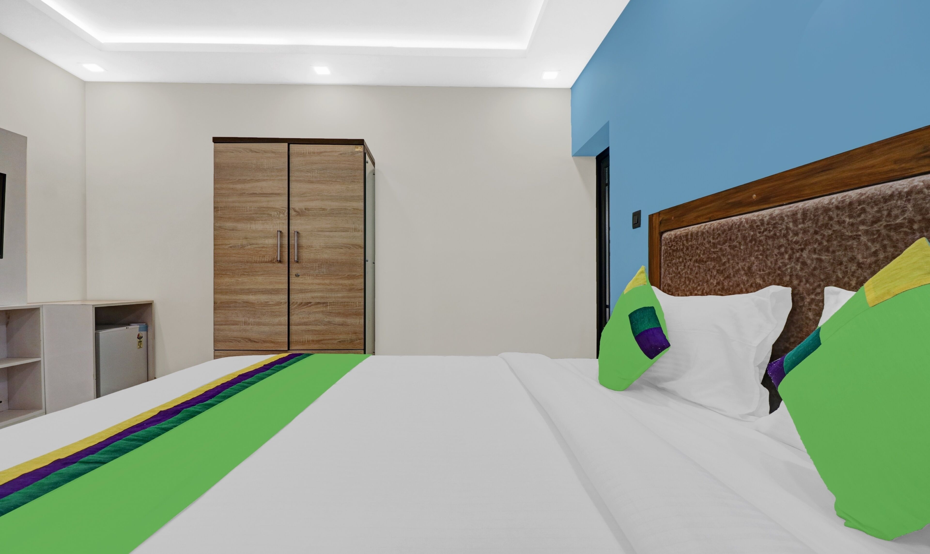 Un dormitorio moderno con una cama grande, un armario y un escritorio pequeño.