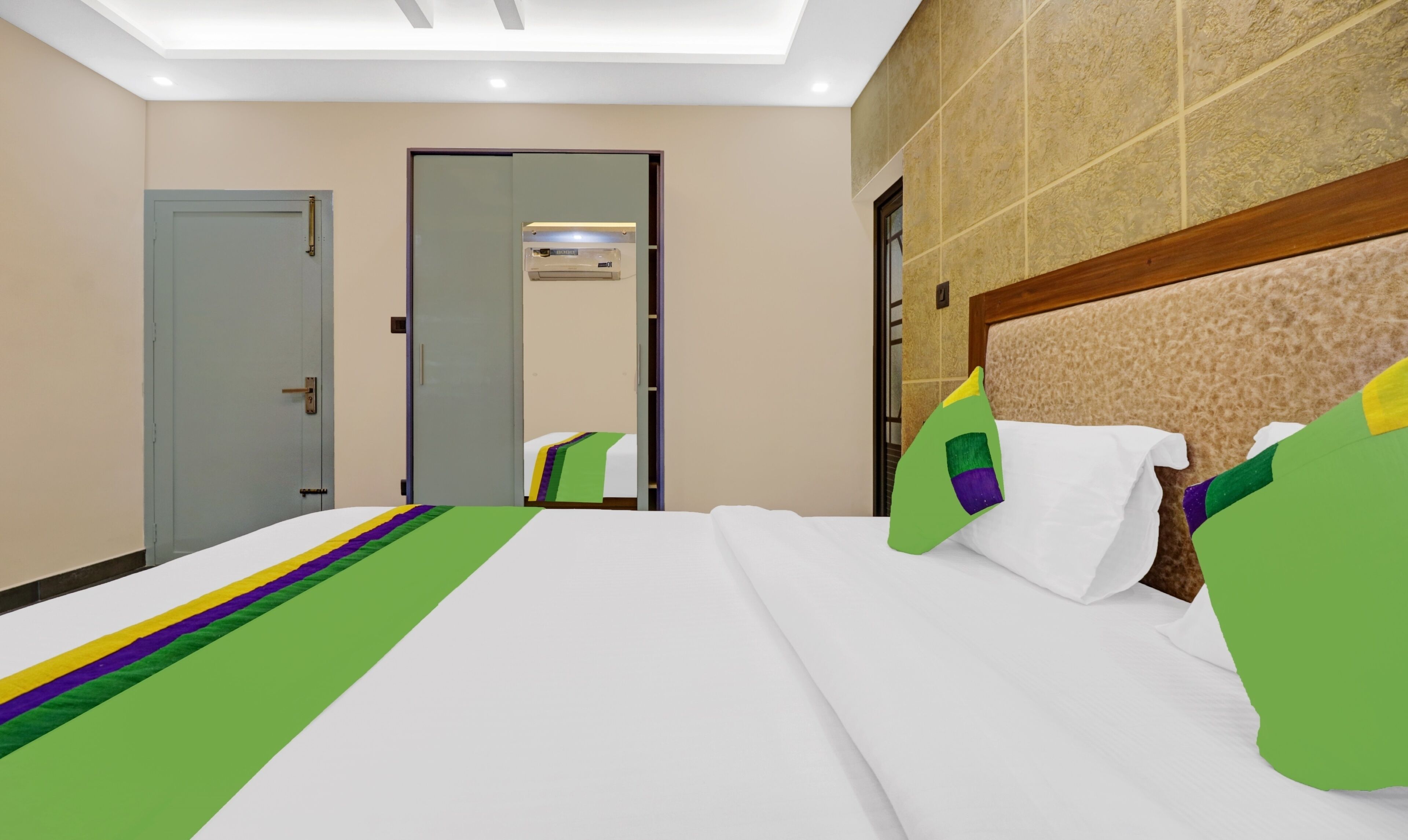 A hotel room with a bed, a door, and a mirror.