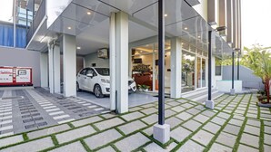 A modern building with a covered entrance, a white car parked inside, and a service area labeled "PUSHPAK SERVICE APTMENT". - Treebo Pushpak 500 mtrs from Chottanikkara temple (Kanayannur)
