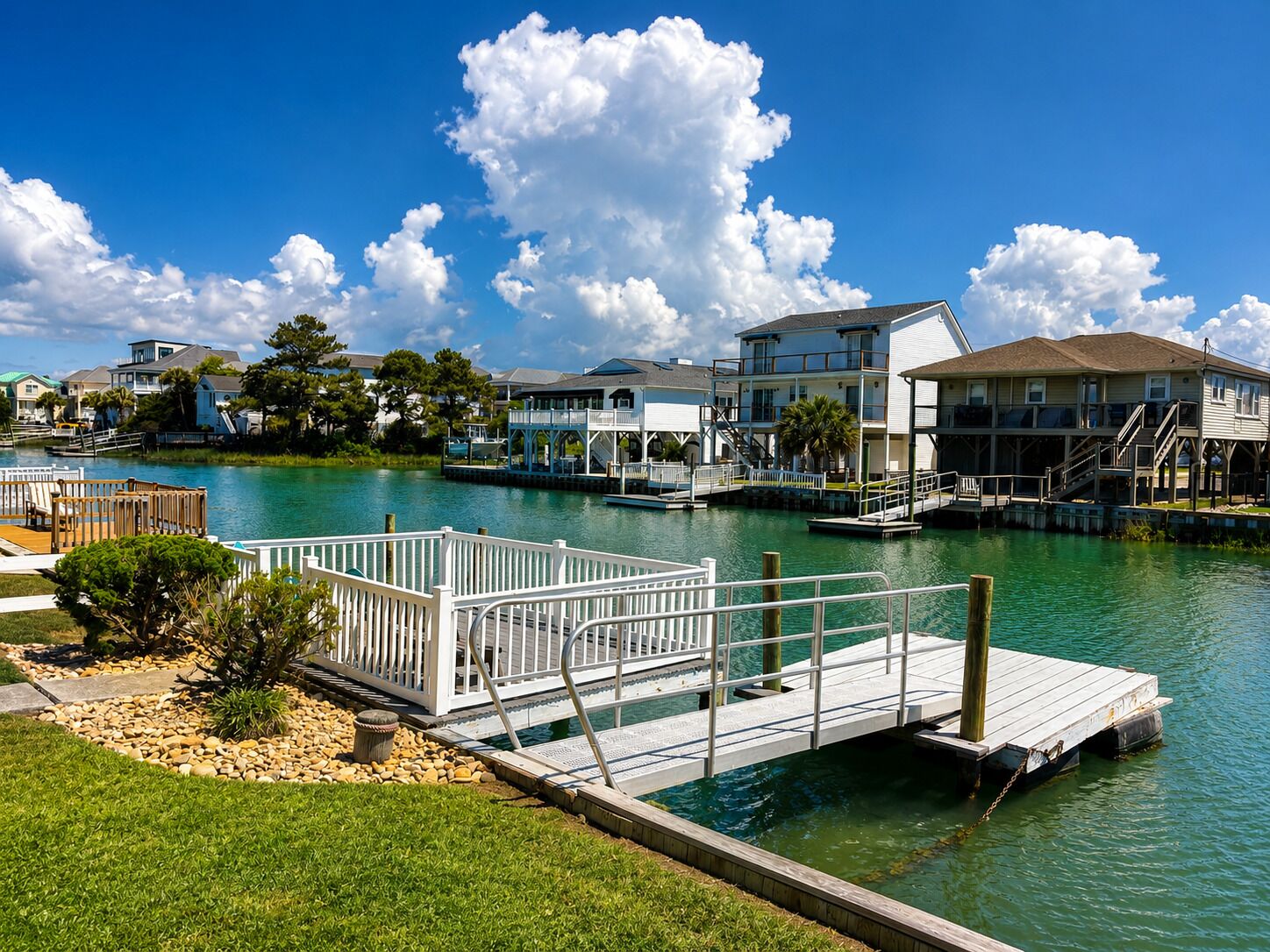 A waterfront property with a dock, a pool, and multiple buildings with balconies.