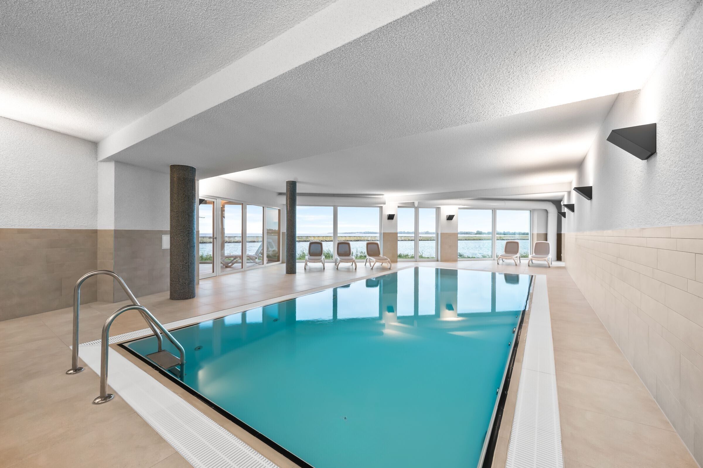 Una gran piscina interior amb vistes clares a l'exterior, un disseny modern i algunes gandules.