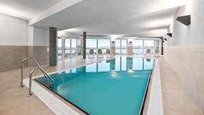 En stor inomhuspool med fri utsikt över omgivningen, modern design och några solstolar.