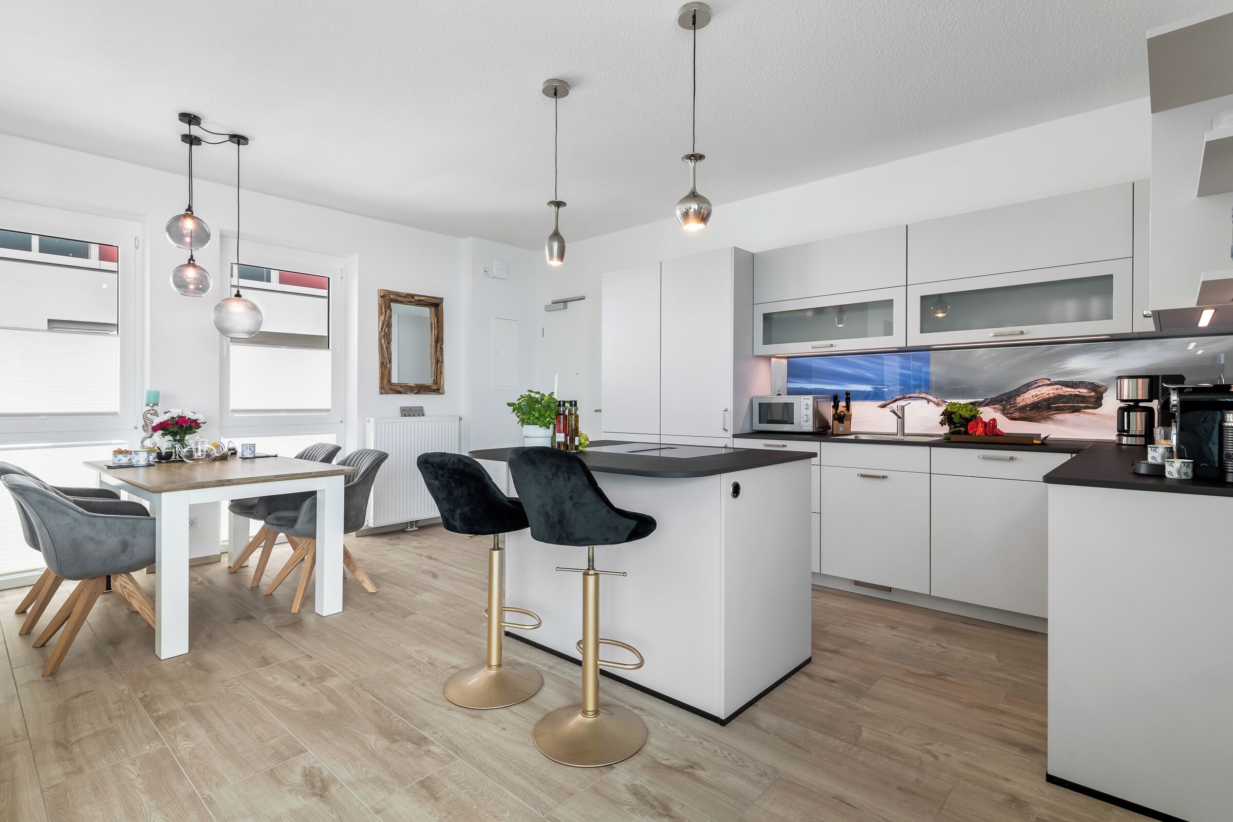 A modern kitchen with white cabinets, a central island, and two bar stools.