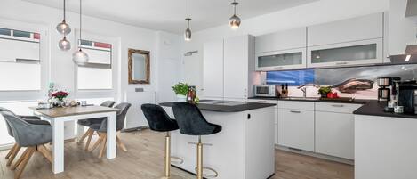 A modern kitchen with white cabinets, a central island, and two bar stools.