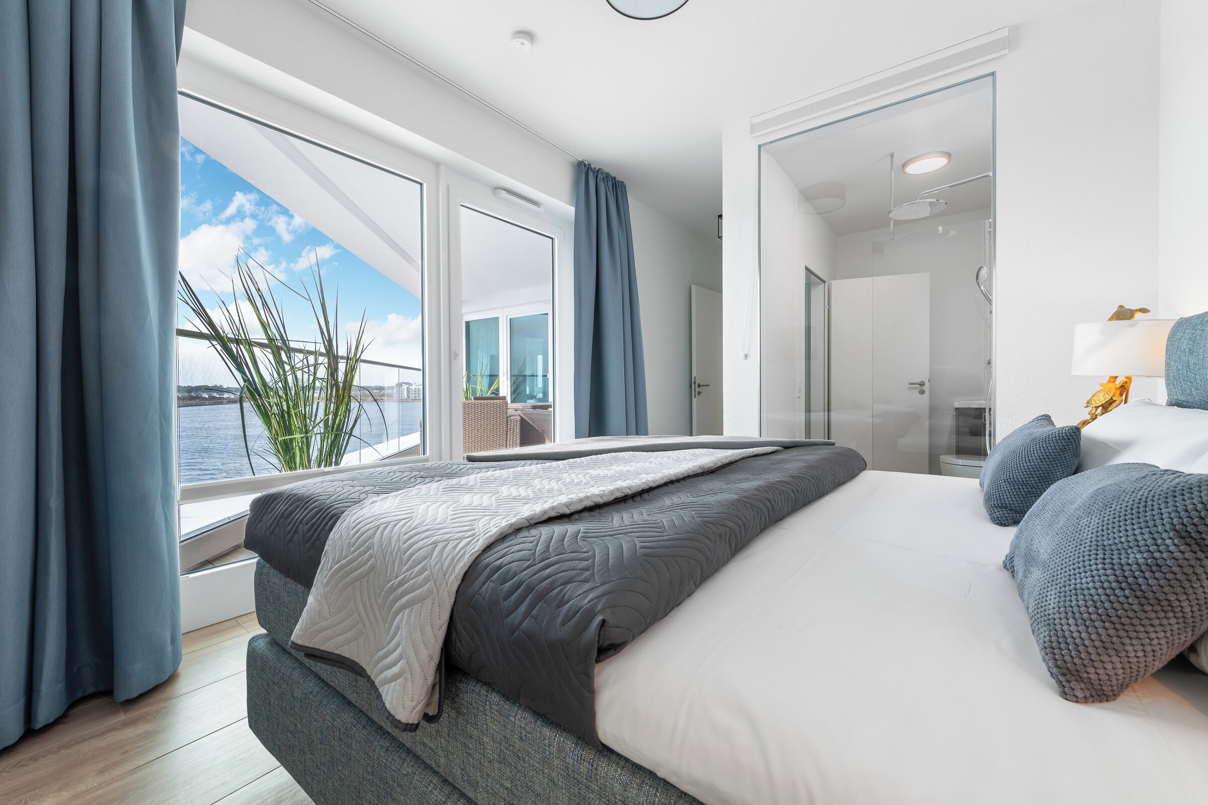 Habitación de hotel moderna con una cama grande, vista al mar y baño independiente.