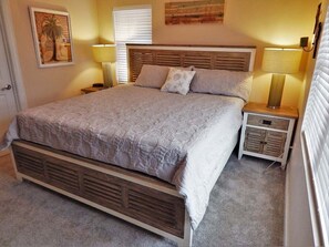 Ein Schlafzimmer mit einem großen Bett, zwei Nachttischen, einer Stehlampe, einer Wanduhr und einem gerahmten Bild.