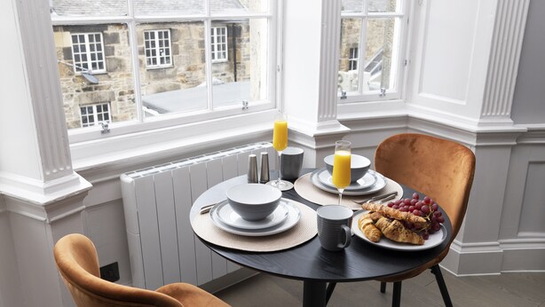 A breakfast setting with a table, chairs, and a view of the outside. - JOIVY Statement Studio On Historic George Street (Edinburgh)