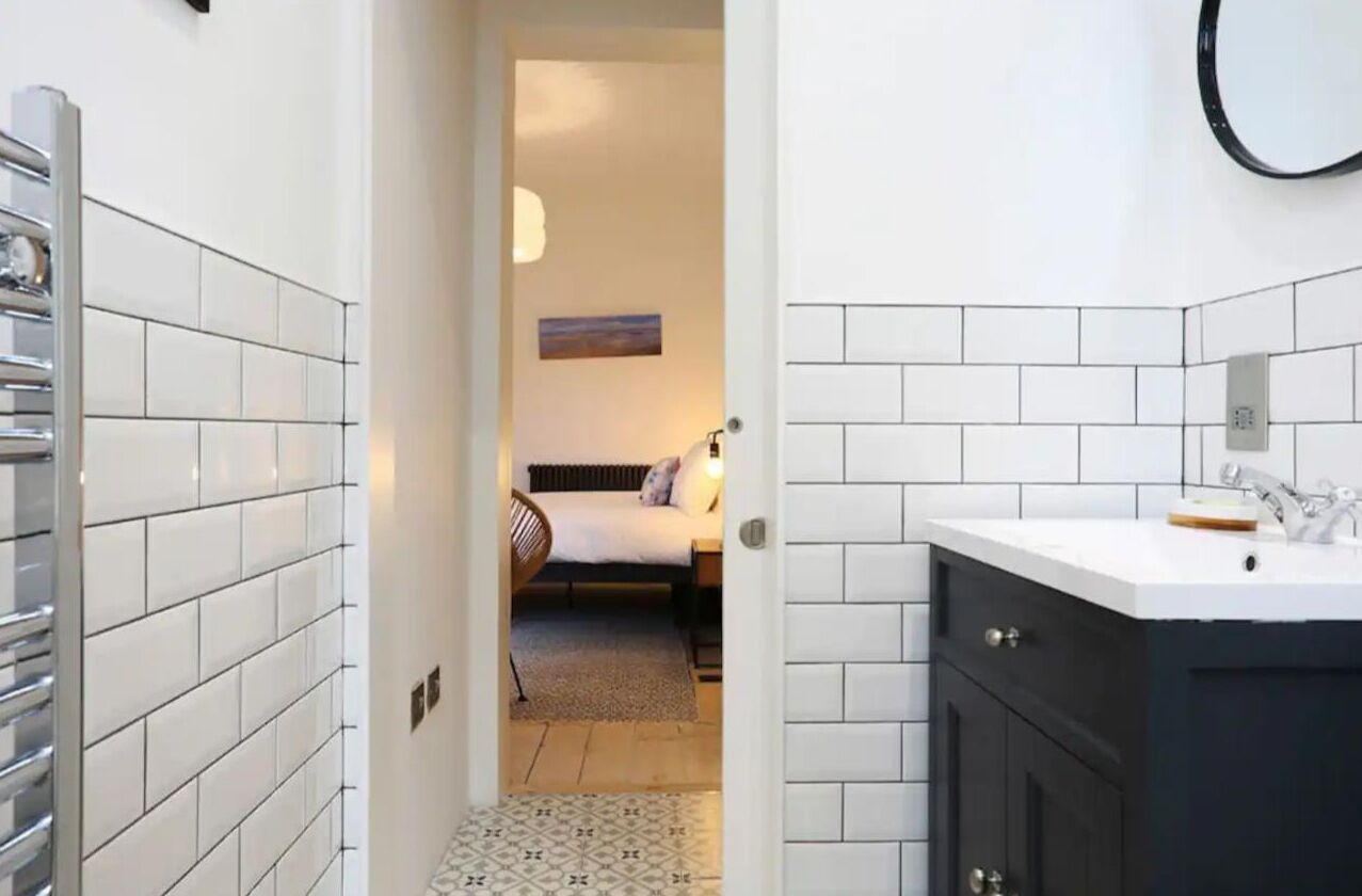 Um banheiro moderno com azulejos brancos, um armário escuro e um porta-toalhas à vista.