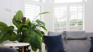 A living room with a grey sofa, a large green plant, and a white table. - JOIVY Luxury House With Patio Next To North Berwick Beach (North Berwick)