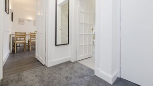 A hallway with a wooden dining table and chairs, a large mirror, and a white door. - JOIVY Beautiful 2-Br Mews Home, Near Princes Street (Edinburgh)
