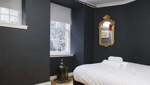 Un dormitorio con cama, ventana, espejo y un farol decorativo.