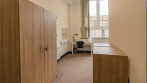 A room with a wooden wardrobe, a desk with a chair, a radiator, and a window with curtains. - JOIVY Meadows Park En-Suite Rooms (Edinburgh)