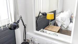 A bedroom with a bed, bedside table, lamp, and a mirror. - JOIVY Meadows Park En-Suite Rooms (Edinburgh)