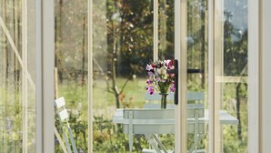 A conservatory with a checkered floor, a table with chairs, and a vase with flowers. - JOIVY The East Lodge At Balcarres (Leven)