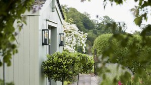A pathway leading to a building with two potted trees and two wall-mounted lights. - JOIVY The East Lodge At Balcarres (Leven)