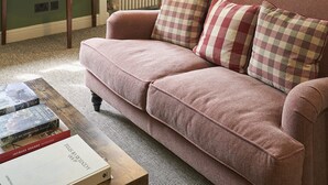 A cozy living room with a green wall, a pink sofa, a wooden coffee table, and a framed picture on the wall.