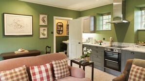A cozy living room with a sofa and armchairs, a kitchen with a built-in oven, and a dining area with a table and chairs.