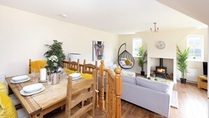 A dining area with a wooden table set for four, a sofa, and a fireplace. - JOIVY Greenknowes Cottage W/ Hot Tub & Fireplace (Kelty)