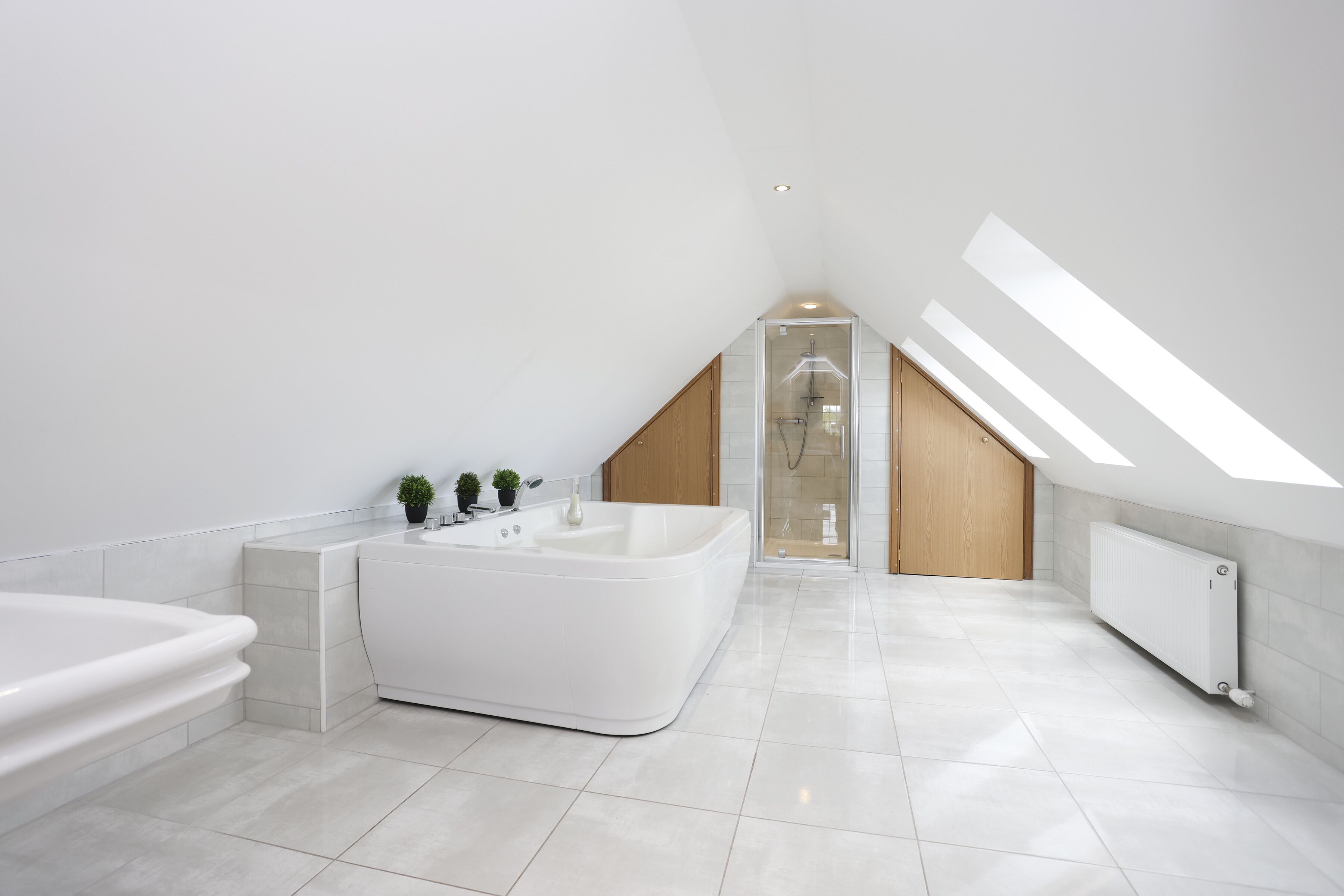 A modern bathroom with a freestanding bathtub, a shower, and a skylight.