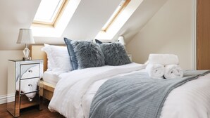 A bedroom with a skylight, a bedside table with a lamp, a bed with rolled towels, and a grey throw blanket. - JOIVY Greenknowes Lodge With Hot Tub And Wood Burning Stove (Kelty)