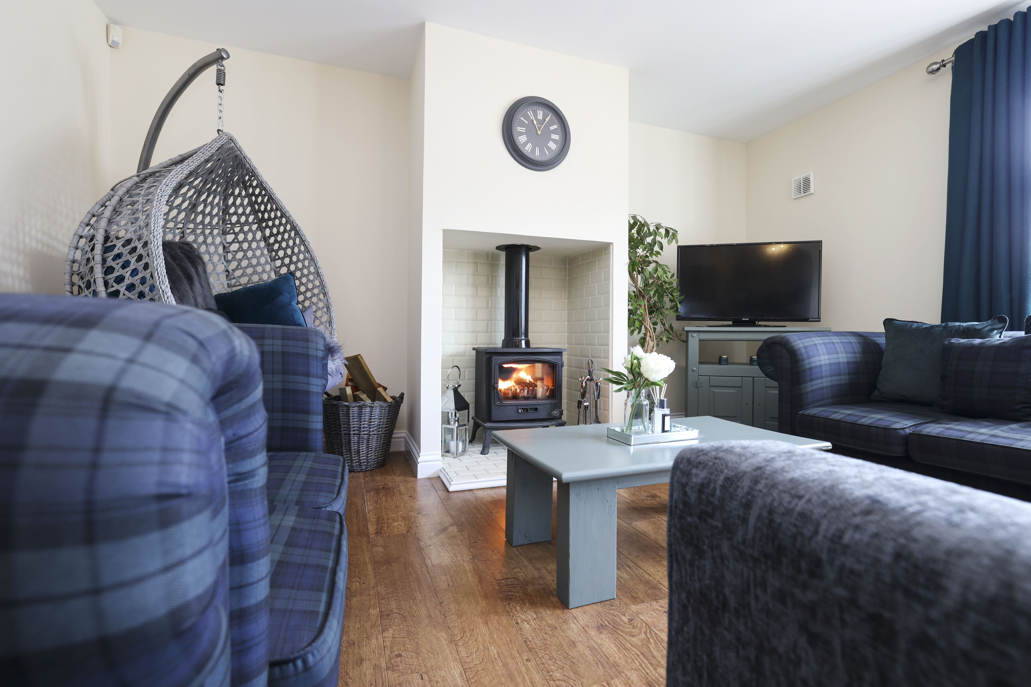 Ein modernes Wohnzimmer mit einer Couch, einem Hängekorbstuhl, einem Kamin, einem Fernseher und einem Esstisch.