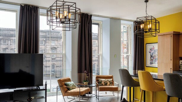 Een moderne woonkamer met een grote televisie, comfortabele zithoek en grote ramen met uitzicht op de stad.