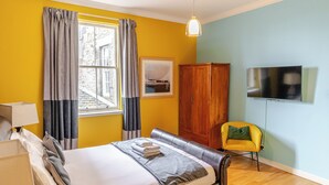 Een hotelkamer met een bed, een houten kledingkast, een televisietoestel en een raam met gordijnen.