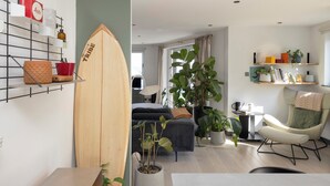 Ett modernt vardagsrum med en surfbräda, en soffa, en fåtölj och en matplats.