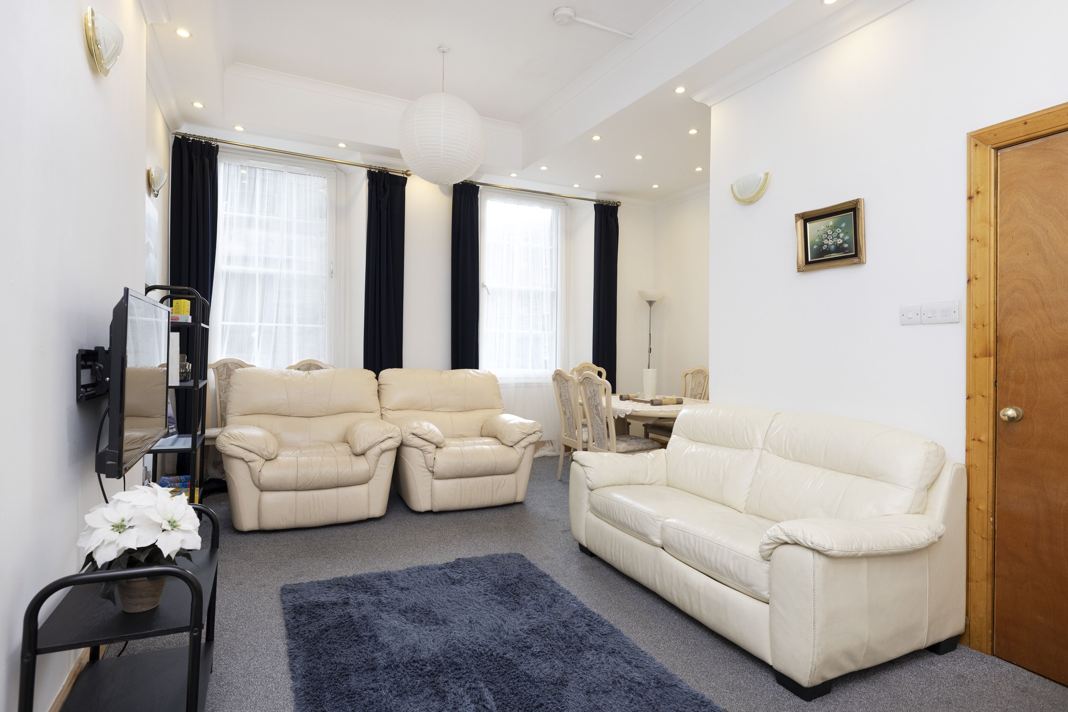 A living room with two beige sofas, a coffee table, a TV on a stand, and a wooden door.