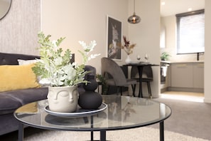 Un salon moderne avec une table basse en verre, un canapé et des vases décoratifs.