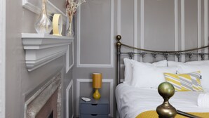 Une chambre à coucher bien rangée, avec un lit, une table de chevet, une lampe et des objets décoratifs.