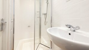 Un baño moderno con ducha acristalada, lavabo blanco y espejo.