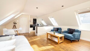 A modern loft apartment with a high ceiling, a dining area, a kitchenette, and a living room with a sofa and a coffee table. - JOIVY Inviting Flat Near Edinburgh Castle W/ Parking (Edinburgh)