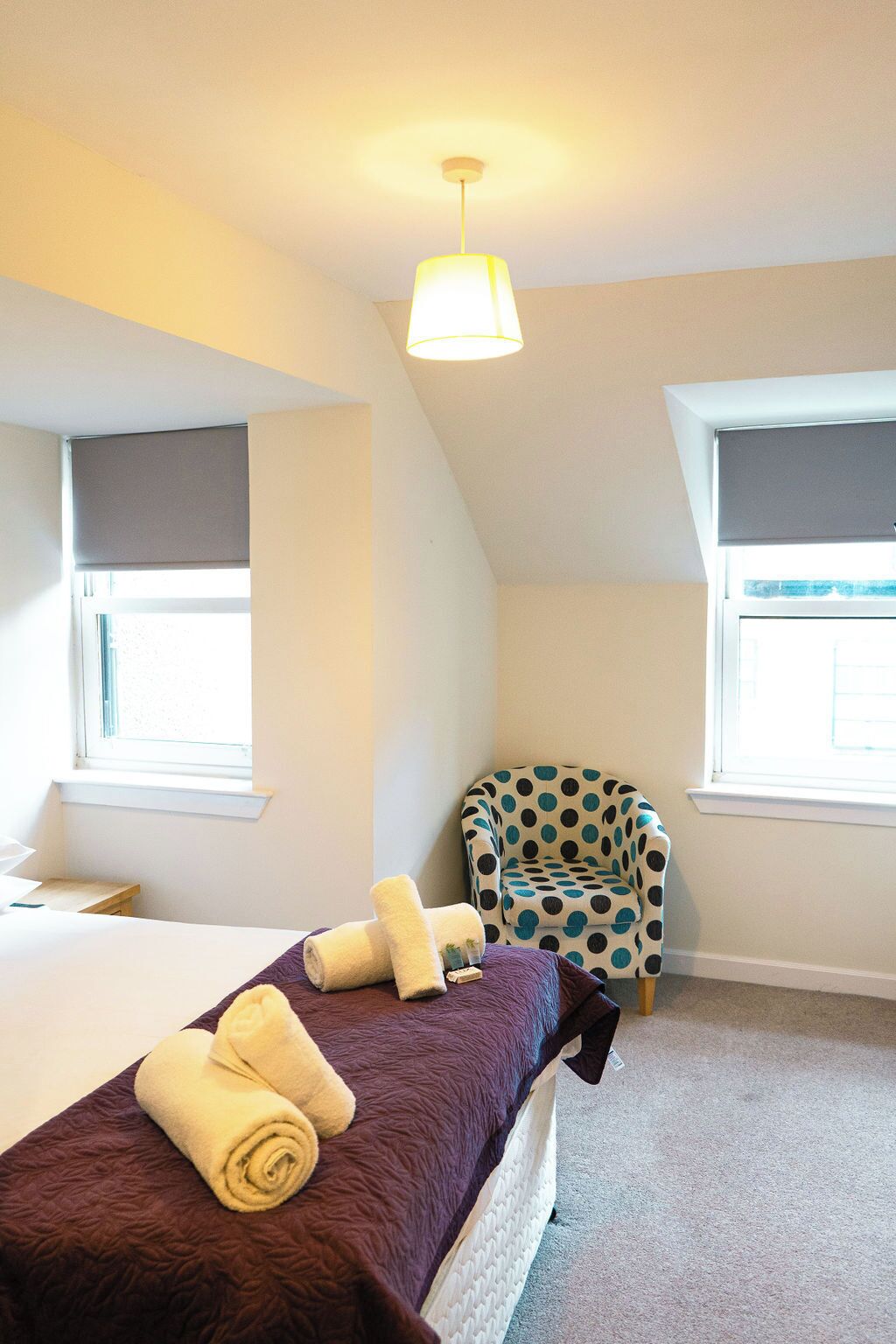 A bedroom with a bed, a chair, and a window.