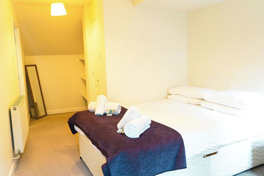 Una habitación de hotel con una cama, un radiador, un espejo y toallas sobre la cama.