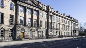 A historic building with large windows and columns, a prominent entrance, and a sidewalk in front. - JOIVY Splendid 2-Br Apartment In New Town (Edinburgh)